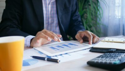 person in black suit jacket holding white tablet computer